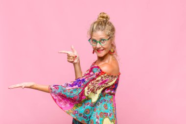 Orta yaşlı kadın gülümsüyor, mutlu, kaygısız ve tatmin olmuş hissediyor, fotokopi alanındaki konsepte veya fikre işaret ediyor.