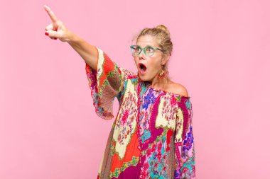 Orta yaşlı bir kadın şaşkın ve şaşırmış hissediyor. Şaşırmış ve ağzı açık bir şekilde hayranlıkla yukarı bakıyor.