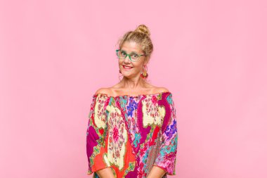 Orta yaşlı kadın pozitif ve kendinden emin gülümsüyor. Tatmin olmuş, arkadaş canlısı ve mutlu görünüyor.