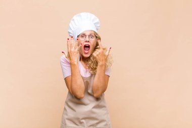 Orta yaşlı kadın fırıncı gülümsüyor ve arkadaş canlısı görünüyor, 7 ya da 7 numarayı gösteriyor, eli önde, geriye doğru sayıyor