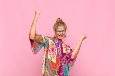 Orta yaşlı bir kadın muzaffer bir şekilde bağırıyor, heyecanlı, mutlu ve şaşırmış görünüyor, kutlama yapıyor.