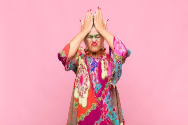 Orta yaşlı bir kadın stresli ve endişeli, depresif ve hayal kırıklığına uğramış hissediyor, iki elini de başa kaldırıyor.