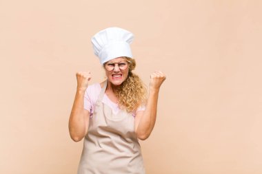 Orta yaşlı fırıncı kendini mutlu, pozitif ve başarılı hissediyor zaferi, başarıları ya da iyi şansı kutluyor.