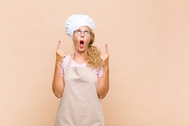 Orta yaşlı kadın fırıncı korkuyla ve ağzı açık bir şekilde şaşkın ve şaşkın bir bakışla yukarı bakıyor.