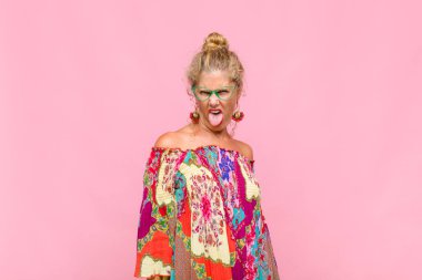 Orta yaşlı bir kadın tiksinmiş ve rahatsız olmuş hissediyor. Dilini dışarı çıkarıyor. İğrenç ve iğrenç bir şeyden hoşlanmıyor.