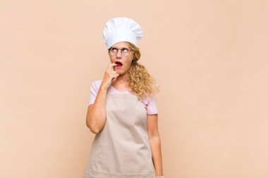 Orta yaşlı fırıncı kadın şaşırmış, gergin, endişeli ya da korkmuş bakışlarıyla, fotokopi alanına doğru bakıyor.