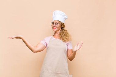 Orta yaşlı kadın fırıncı gülümsüyor, kendinden emin, başarılı ve mutlu hissediyor, fotokopi alanında fikir veya konsept gösteriyor.