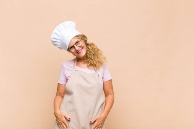 Orta yaşlı fırıncı neşeli, mutlu, kendinden emin ve rahat bir ifadeyle gülümsüyor.