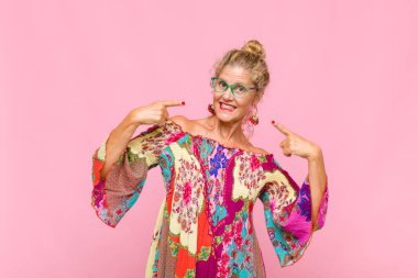 Orta yaşlı kadın kendine güvenerek gülümsüyor. Geniş bir gülümseme, pozitif, rahat, tatmin olmuş bir tavır.