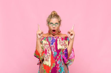 Orta yaşlı bir kadın şaşırmış, şaşırmış ve ağzı açık bir şekilde iki elini de havaya kaldırıp boşluğu dolduruyor.