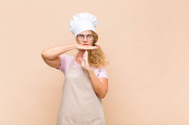 Orta yaşlı fırıncı, ciddi, sert, kızgın ve canı sıkkın görünüyor.