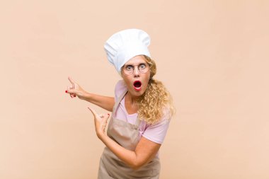 Orta yaşlı fırıncı şaşkın ve şaşırmış hissediyor. Yandaki fotokopi alanını işaret ediyor. Şaşırmış, ağzı açık bir bakış.