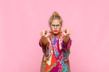 Orta yaşlı bir kadın kameraya iki parmağını ve kızgın bir ifadeyle bakarak sana görevini yapmanı söylüyor.