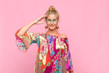 Orta yaşlı bir kadın saygı göstererek, onur ve vatanseverlik adına kameraya selam veriyor.