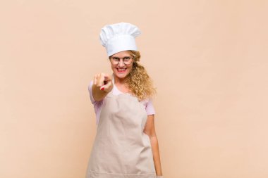 Orta yaşlı bir fırıncı kameraya tatmin olmuş, kendinden emin, dost canlısı bir gülümsemeyle bakıyor ve seni seçiyor.