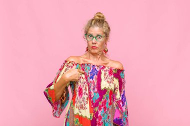 Orta yaşlı bir kadın şaşkın, şaşkın ve güvensiz hissediyor. Kendini gösterip kim olduğunu soruyor, ben mi??