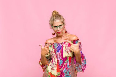 Kötü tavırlı orta yaşlı bir kadın gururlu ve agresif görünüyor, yukarıyı gösteriyor ya da elleriyle alay işareti yapıyor.