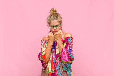 Orta yaşlı kadın kendinden emin, sinirli, güçlü ve agresif görünüyor. Yumrukları boks pozisyonunda dövüşmeye hazır.