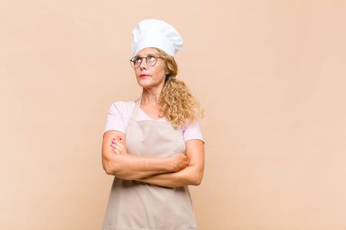 Orta yaşlı fırıncı kendini mutlu, gururlu ve umutlu hisseder, merak eder veya düşünür, çapraz kollarla fotokopi çekmek ister.