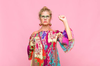 Orta yaşlı kadın ciddi, güçlü ve isyankar hissediyor, yumruğunu kaldırıyor, protesto ediyor ya da devrim için savaşıyor.