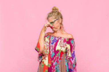 Orta yaşlı bir kadın iğrenç ve nahoş bir koku almaktan kaçınmak için burnunu tutuyor.