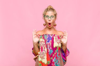 Orta yaşlı kadın şok olmuş, şaşırmış ve şaşırmış hissediyor. Onaylıyor. İki eliyle de onay işareti yapıyor.