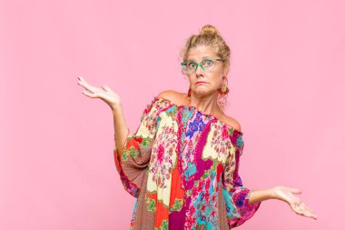 Orta yaşlı kadın şaşkın, kafası karışmış ve stresli görünüyor, farklı seçenekler arasında merak ediyor, kararsız hissediyor.