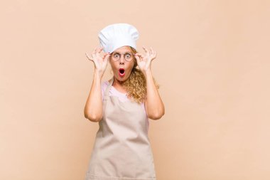 Orta yaşlı fırıncı şaşkın, şaşkın ve şaşırmış hissediyor, elinde şaşkın, inançsız bir bakışla gözlük tutuyor.