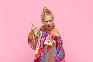 Orta yaşlı bir kadın kızgın agresif bir ifadeyle kameraya bakıyor. Öfkeli, deli bir patron gibi görünüyor.