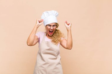 Orta yaşlı bir fırıncı mutlu, şaşırmış ve gururlu hisseder, bağırır ve başarıyı büyük bir gülümsemeyle kutlar.