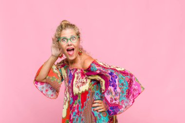 Orta yaşlı kadın gülümsüyor, tuhaf bir şekilde yan tarafa bakıyor, dedikoduları dinlemeye ya da bir sırrı duymaya çalışıyor.