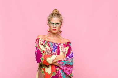 Orta yaşlı bir kadın mutsuz ve hayal kırıklığına uğramış, ciddi görünüyor, kızgın ve kollarını kavuşturmuş.