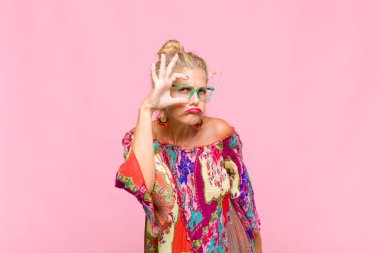 Orta yaşlı bir kadın mutlu bir şekilde gülümsüyor, şaka yapıyor ve gözetleme deliğinden bakıyor, sırları gözetliyor.