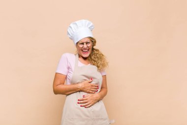 Orta yaşlı bir fırıncı komik bir şakaya yüksek sesle gülüyor, mutlu ve neşeli hissediyor, eğleniyor.