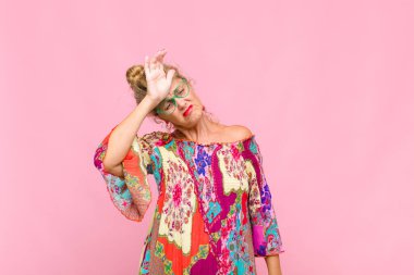 Orta yaşlı kadın stresli, yorgun ve hayal kırıklığına uğramış görünüyor, alnından ter damlıyor, umutsuz ve bitkin hissediyor.