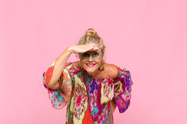 Orta yaşlı kadın şaşkınlık ve şaşkınlık içinde bakıyor. Alnı açık, uzaklara bakıyor, izliyor ya da arıyor.