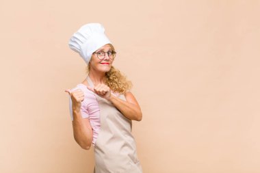Orta yaşlı fırıncı neşeli bir şekilde gülümsüyor ve yan taraftaki fotokopi alanını işaret ediyor, mutlu ve tatmin olmuş hissediyor.