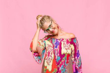 Orta yaşlı bir kadın neşeli ve tesadüfen gülümsüyor, olumlu, mutlu ve kendinden emin bir bakışla göğüs göğüse tutuşuyor.