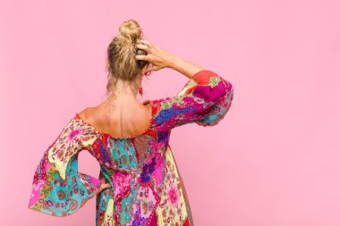 Orta yaşlı bir kadın bilgisiz ve kafası karışık, bir çözüm düşünüyor, eli kalçasında, diğeri kafasında, dikiz aynasından.