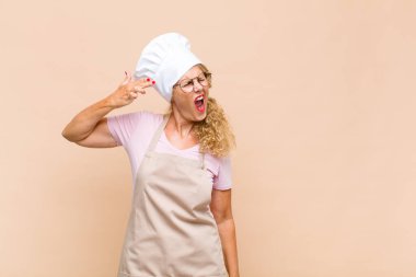 Orta yaşlı kadın fırıncı mutsuz ve stresli görünüyor, intihar jesti elle silah işareti yapıyor, kafasını işaret ediyor.