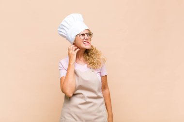 Orta yaşlı bir fırıncı stresli, hayal kırıklığına uğramış ve yorgun, endişeli ve sorunlu bir bakışla boynunu ovalıyor.