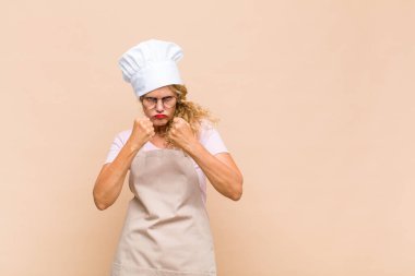 Orta yaşlı fırıncı kendinden emin, sinirli, güçlü ve agresif görünüyor. Yumrukları boks pozisyonunda dövüşmeye hazır.