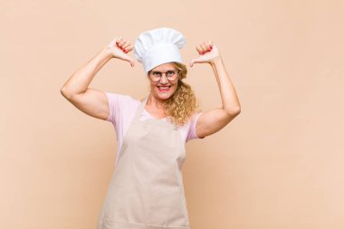 Orta yaşlı kadın fırıncı üzgün, hayal kırıklığına uğramış ya da kızgın görünüyor. Anlaşmazlıkta baş parmağını gösteriyor, hayal kırıklığına uğramış hissediyor.