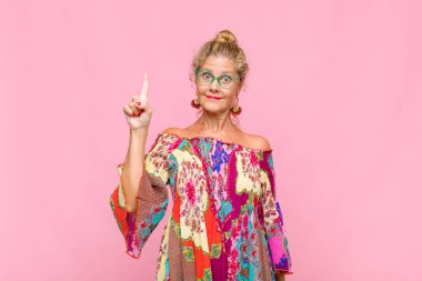 Orta yaşlı kadın mutlu bir şekilde gülümsüyor, tek eliyle boşluğu dolduruyor.