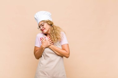 Orta yaşlı fırıncı üzgün, yaralı ve kalbi kırık görünüyor, iki elini de kalbe yakın tutuyor, ağlıyor ve bunalımda.