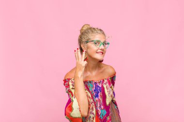 Orta yaşlı bir kadın gülümsüyor ve arkadaş canlısı görünüyor. Elleri önde, geriye doğru sayıyor.