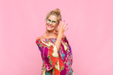 Orta yaşlı bir kadın gülümsüyor ve arkadaş canlısı görünüyor. 5 ya da 5 numarayı gösteriyor.