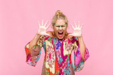 Panik içinde bağıran orta yaşlı bir kadın, şok olmuş, korkmuş ya da öfkeli, elleri başının yanında.