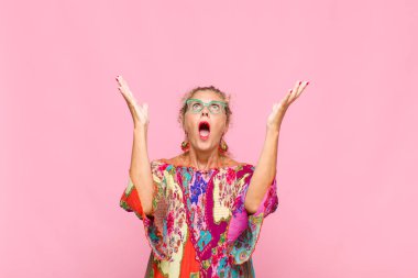 Orta yaşlı bir kadın kendini mutlu, şaşkın, şanslı ve şaşırmış hissediyor. Zaferi iki eli havada kutluyor.