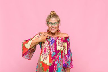 Orta yaşlı kadın mutlu, gururlu ve şaşırmış görünüyor, neşeli bir şekilde kendini gösteriyor, kendinden emin ve kibirli hissediyor.